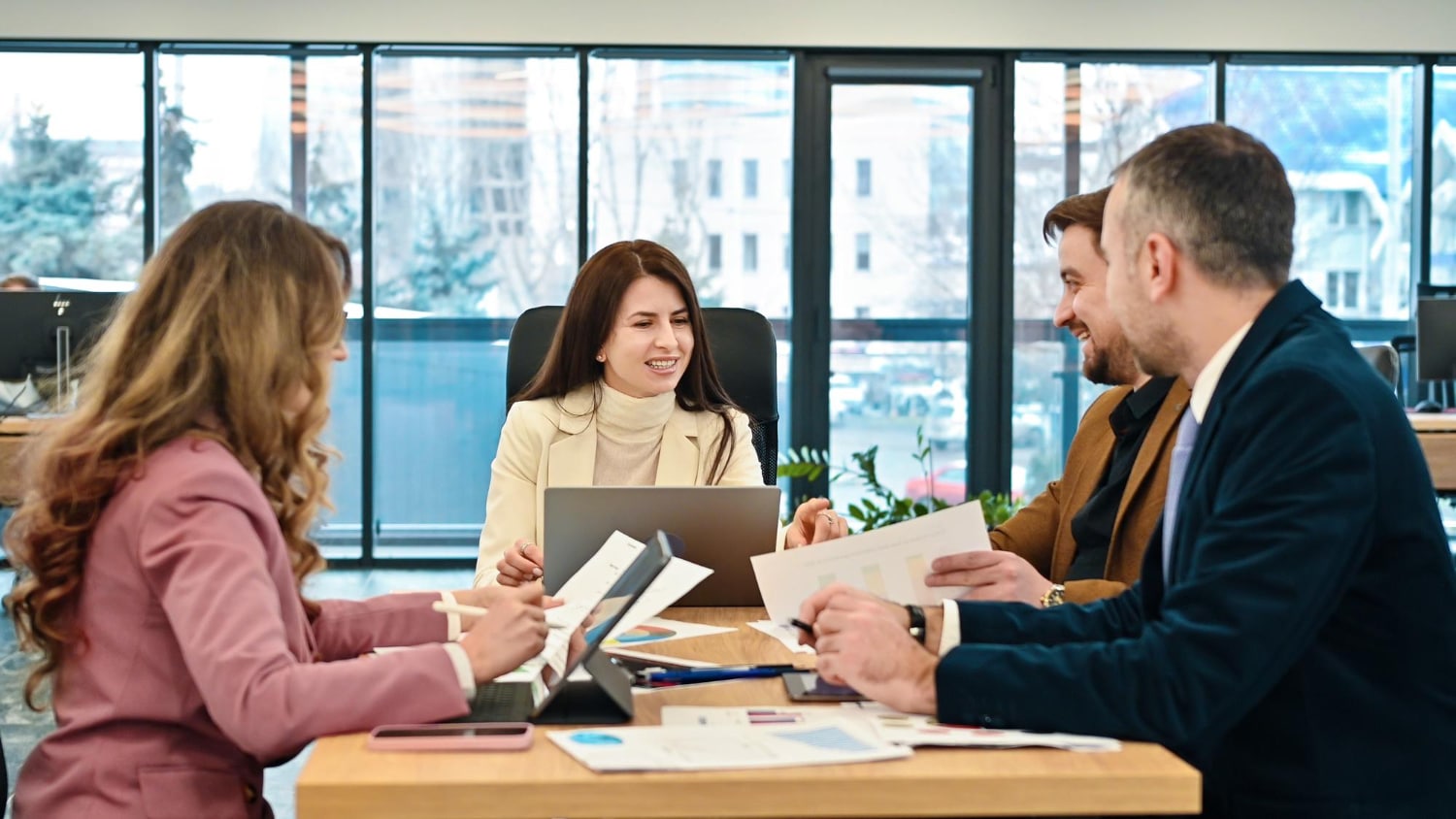 A group of business persons discuss using charts and a laptop.