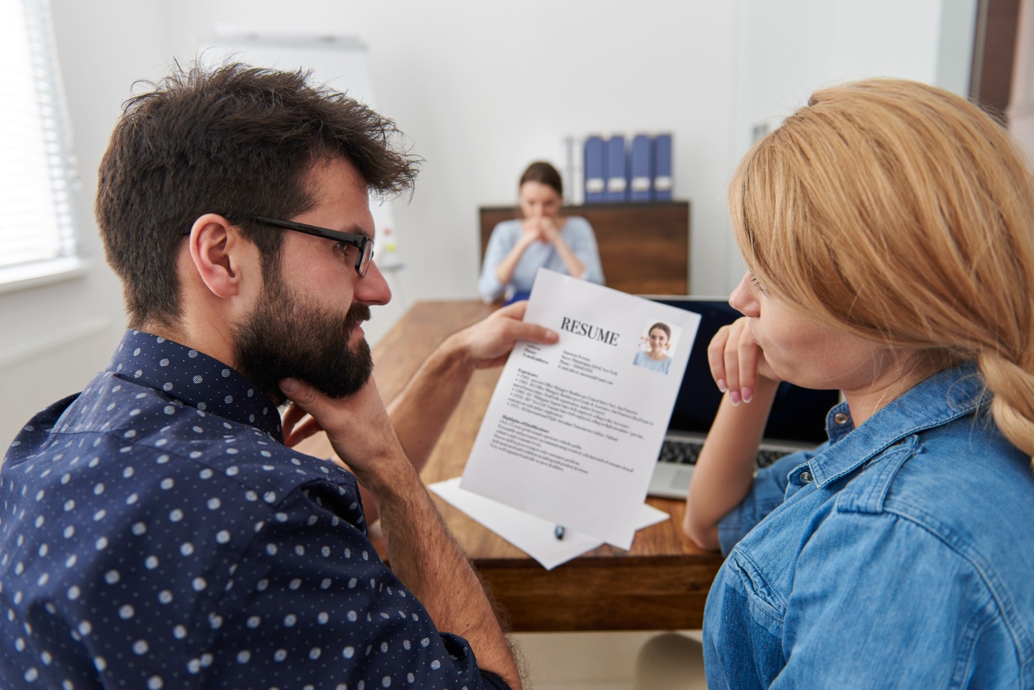 A woman and a man see each other while discussing a resume in an interview.